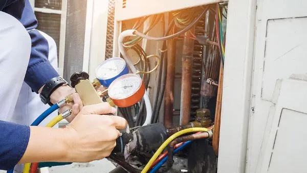 American Heating & Air Plus technician checking refrigerant pressure during an emergency AC repair near Lake Geneva, WI